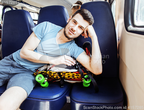 Image of young pretty modern hipster guy traveller on train with skateboa