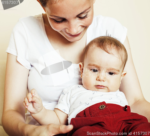 Image of young brunette happy mother holding toddler baby son, breast-fee