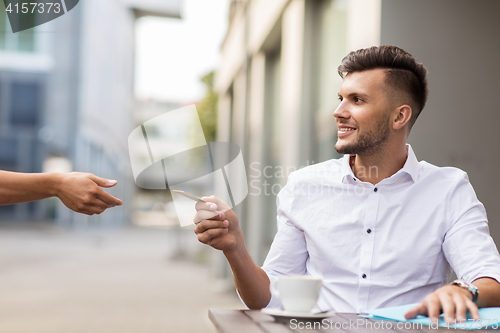 Image of man with credit card paying for coffee at cafe