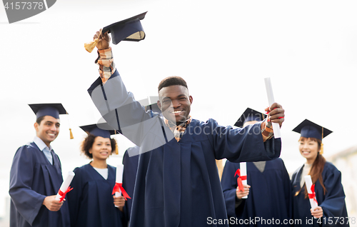 Image of happy students in mortar boards with diplomas