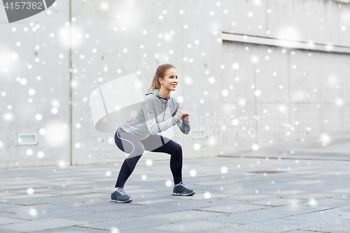 Image of happy woman doing squats and exercising outdoors