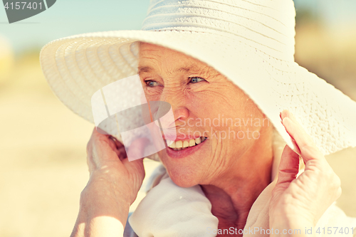 Image of happy senior woman in sun hat on summer beach