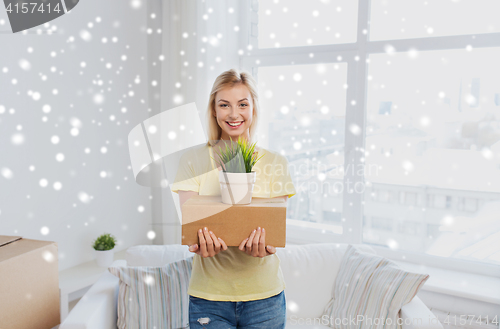 Image of smiling young woman with box and plant at home