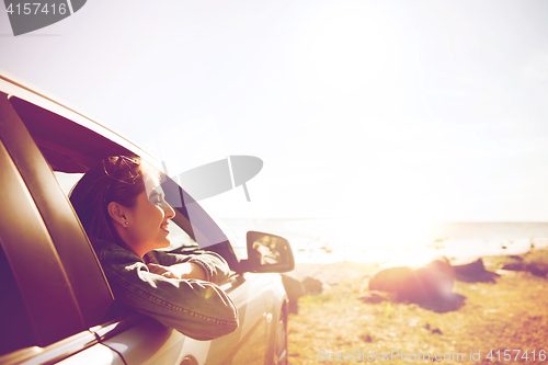 Image of happy teenage girl or young woman in car