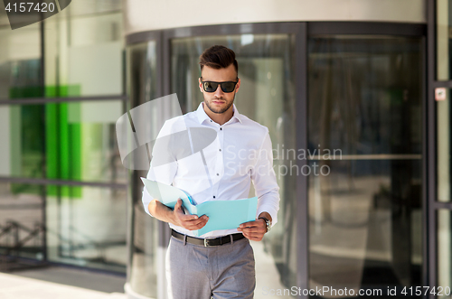 Image of young man with business file on city street