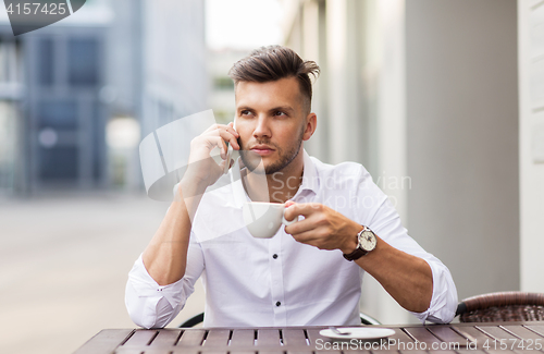 Image of man with coffee calling on smartphone at city cafe