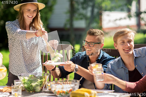 Image of happy friends having dinner at summer garden party