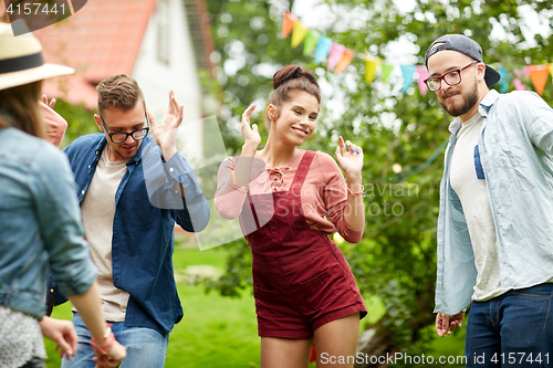 Image of happy friends dancing at summer party in garden