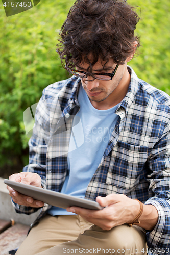 Image of man in glasses with tablet pc computer outdoors