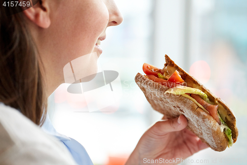 Image of close up of happy woman eating panini sandwich