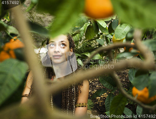 Image of Young cute smiling woman in park with oranges