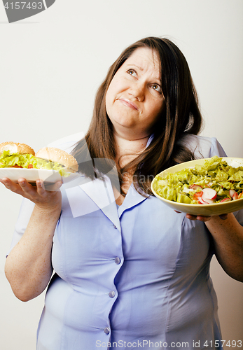 Image of fat white woman having choice between hamburger and salad close 