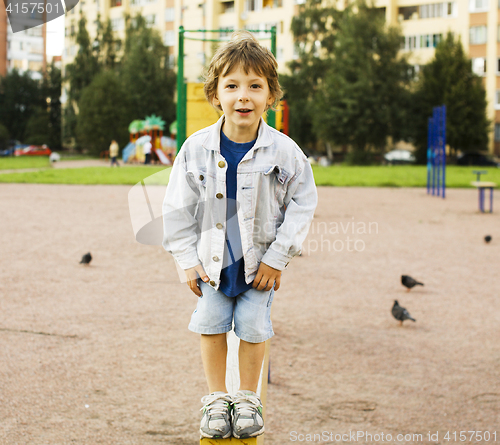 Image of little cute boy playing on playground, hanging on gymnastic ring