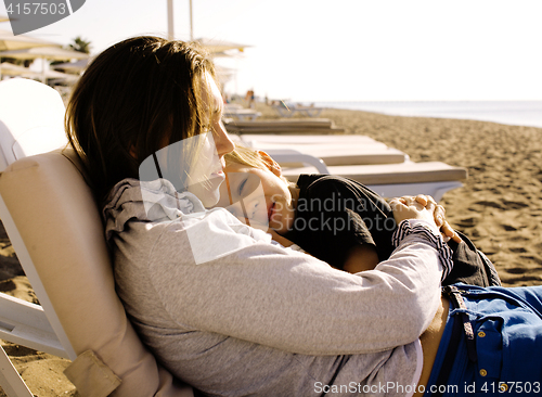 Image of young mother with son resting on sea coast, happy family togethe