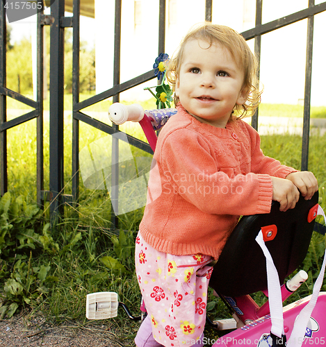 Image of little girl with mother outside walking on playground, riding bi