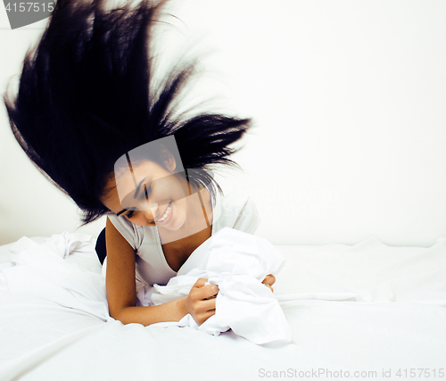 Image of young pretty tann woman in bed among white sheets having fun, tr