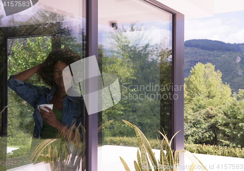 Image of African American woman drinking coffee looking out the window