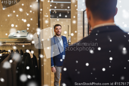 Image of man trying jacket on at mirror in clothing store