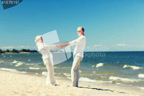 Image of happy senior couple holding hands on summer beach