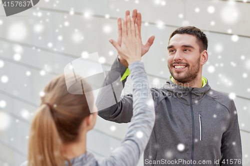 Image of happy couple giving high five outdoors