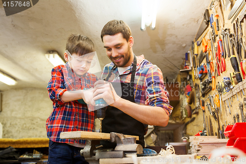 Image of father and son with drill working at workshop