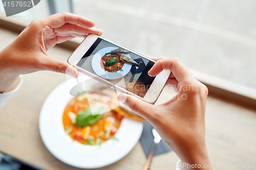 Image of hands with smartphone photographing food