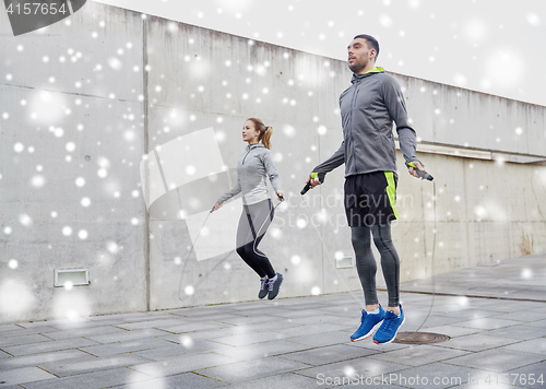 Image of man and woman exercising with jump-rope outdoors