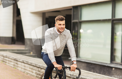 Image of young man riding bicycle on city street