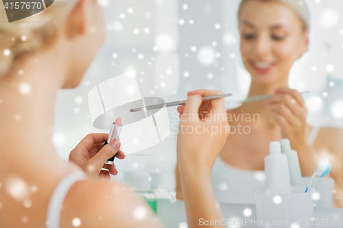 Image of woman with lipstick and make up brush at bathroom