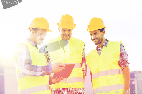 Image of smiling builders in hardhats with tablet pc