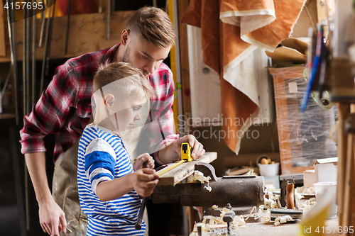 Image of father and son with ruler measure wood at workshop