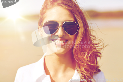 Image of smiling young woman in sunglasses on beach