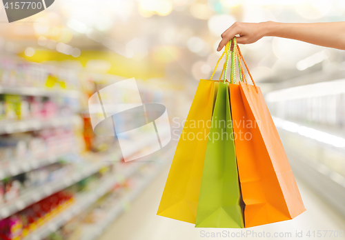 Image of hand with shopping bags over supermarket