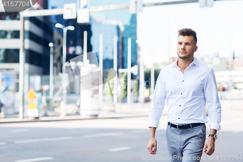 Image of young man walking along city street