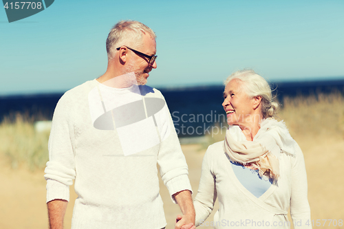 Image of happy senior couple holding hands on summer beach