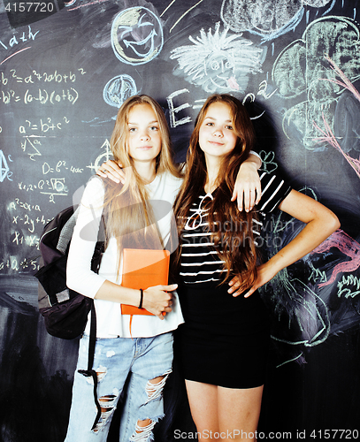 Image of back to school after summer vacations, two teen real girls in classroom with blackboard painted together