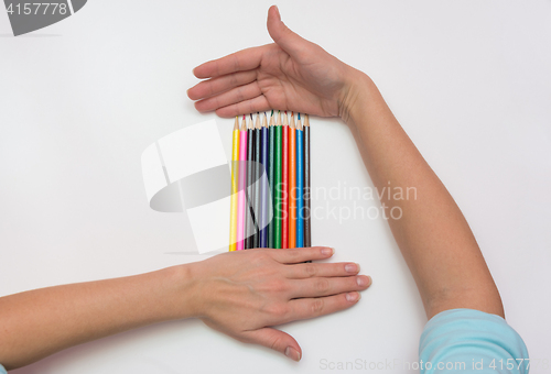 Image of On a sheet of paper lie pencils Female hands lie above and below them