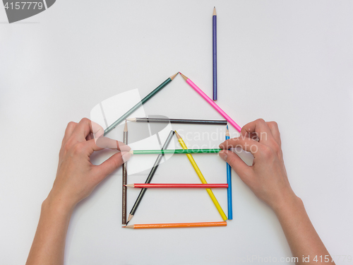 Image of Female hands gently put a pencil next to the house layout, close-up