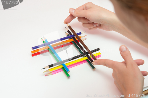 Image of She builds the pinnacle of pencils on a sheet of white paper