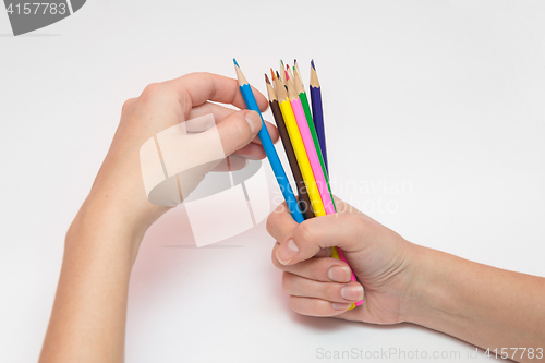 Image of Female hand holding a fist around a dozen pencils, the other hand selects the desired color