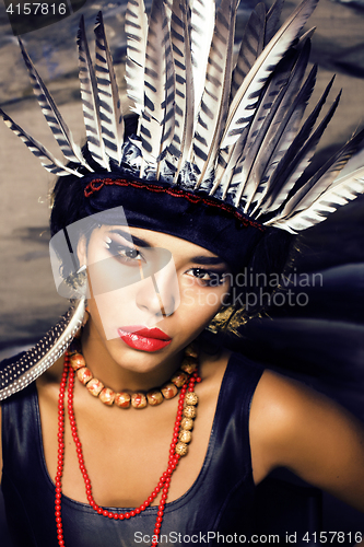 Image of young pretty woman with make up like red indian, futher in hair,