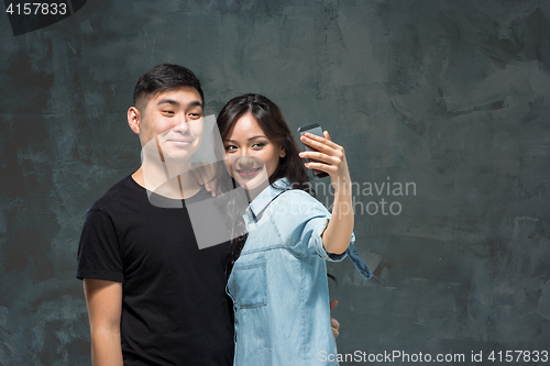 Image of Portrait of smiling Korean couple on a gray