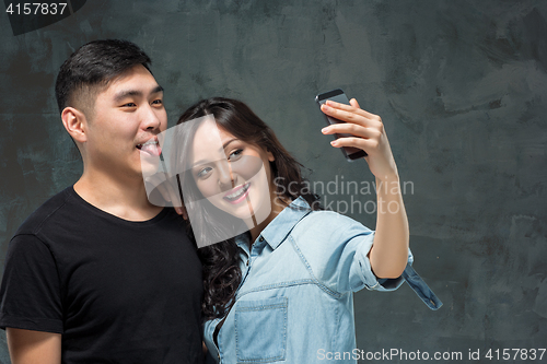 Image of Portrait of smiling Korean couple on a gray