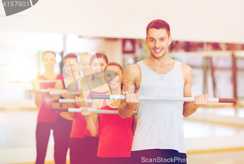 Image of group of smiling people working out with barbells