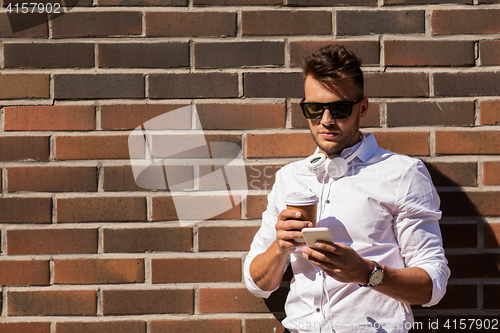 Image of man with smartphone and coffee cup on city street