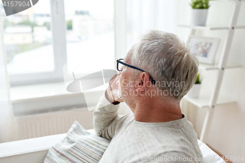 Image of senior man in glasses thinking at home