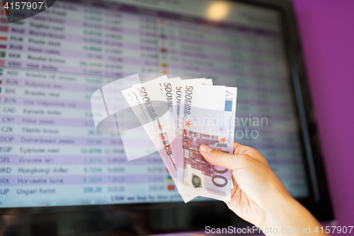 Image of hand with euro money over currency exchange rates