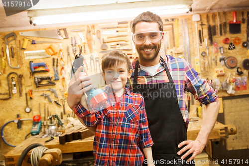 Image of father and son with drill working at workshop