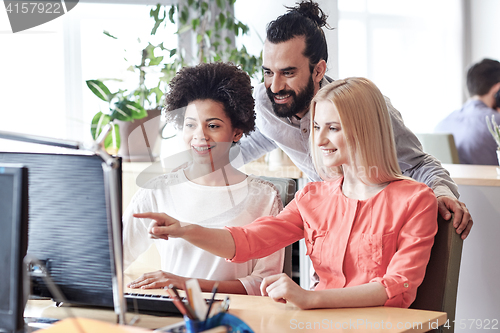 Image of happy creative team with computer in office