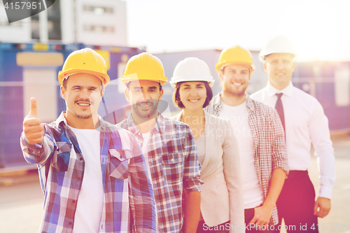 Image of group of smiling builders in hardhats outdoors